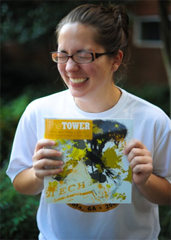 Emily with big smile and eyes closed, holding up a copy of The Tower.